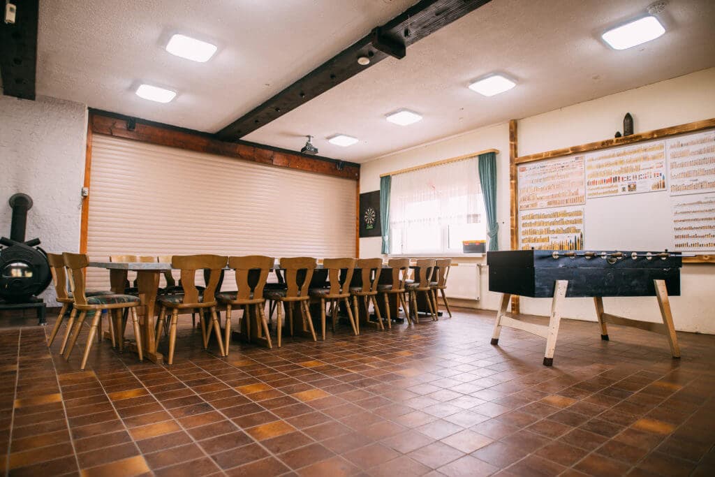 Gastraum des Schützenhauses mit langer Tafel, Kicker und Ofen